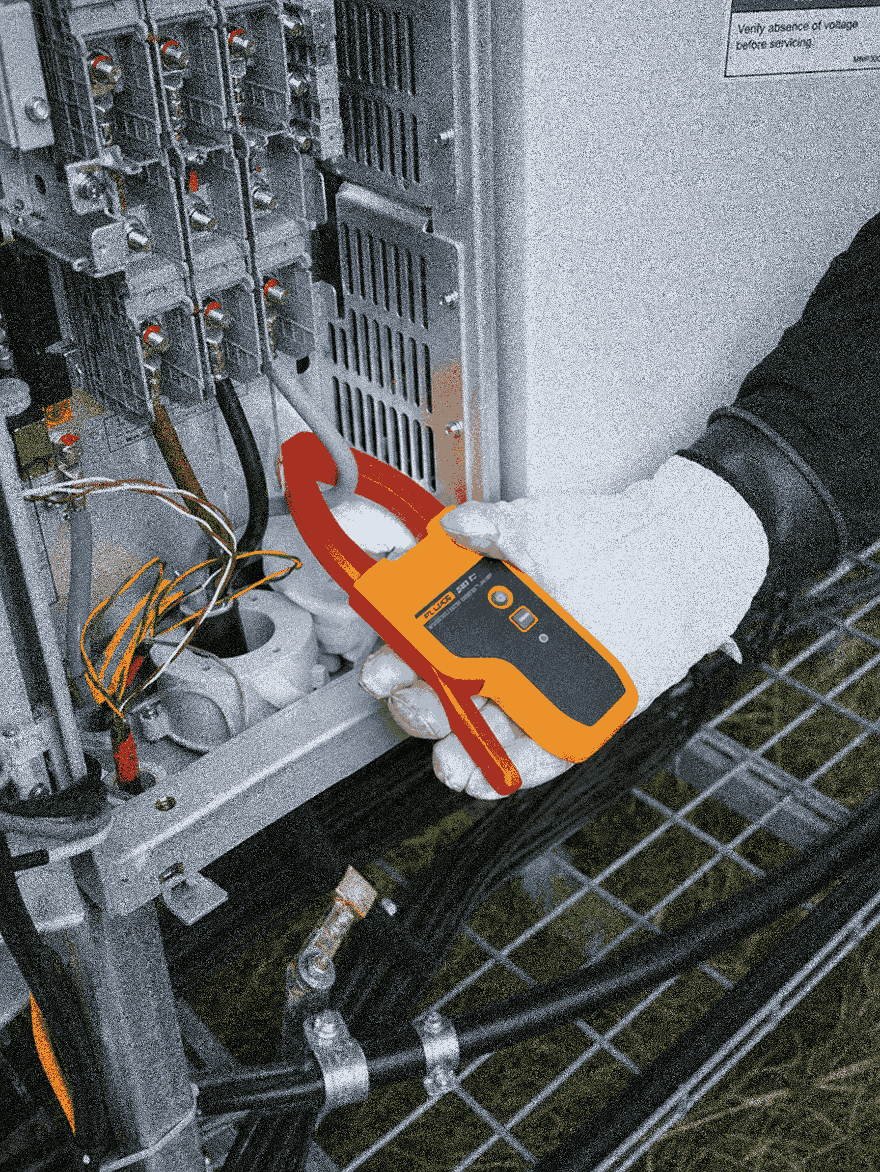 Person using a clamp meter on electrical equipment